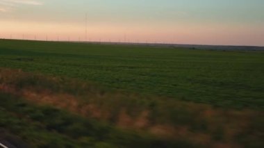 Pencereden yüksek hızlı tren manzarası güzel doğa manzarası vahşi arazi ve orman rayları yaz arkaplanında akşam günbatımında tren rayları. Ulaşım, seyahat, demiryolu, iletişim konsepti