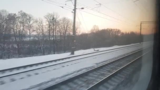 Vista da janela do trem de alta velocidade na paisagem da bela natureza campo frio gelado nevado selvagem e árvores nuas floresta pôr do sol da noite ensolarado em fundo de inverno. Transporte, viagens, conceito ferroviário — Vídeo de Stock