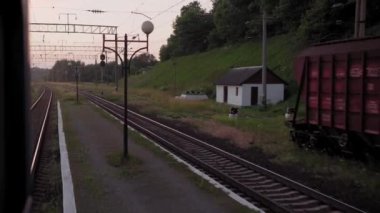 Terk edilmiş eski istasyon ve paslı yük vagonları üzerindeki yüksek hızlı trenden manzara. Tren rayları akşam gökyüzü günbatımında yaz arkaplanında. Ulaşım, seyahat, demiryolu, iletişim konsepti