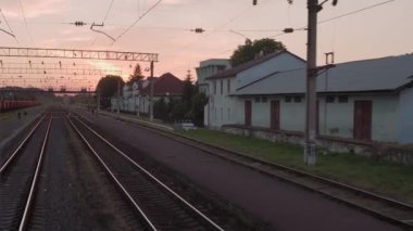 Pencereden yüksek hızlı tren manzarası güzel doğa manzarası vahşi arazi ve orman rayları yaz arkaplanında akşam günbatımında tren rayları. Ulaşım, seyahat, demiryolu, iletişim konsepti