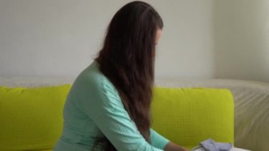 Not Defteri Hazırlama çantalarıyla doğum hastanesi için paketleme listesi hazırlayan sevimli hamile kadın. Hamilelikteki genç Ledy 'nin evde koltukta keyfi yerinde. Annelik, Sağlık ve Bakım Konsepti