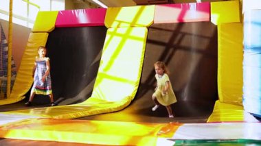 Playroom 'da koşuşturan Küçük, Sevimli Tamirci Kızlar. Çocuklar Trambolinde Atlıyor Çocuk Eğlence Merkezi 'nde. Çocuk parkında eğleniyor. Çocukluk, Geliştirme, Eğlence Konsepti