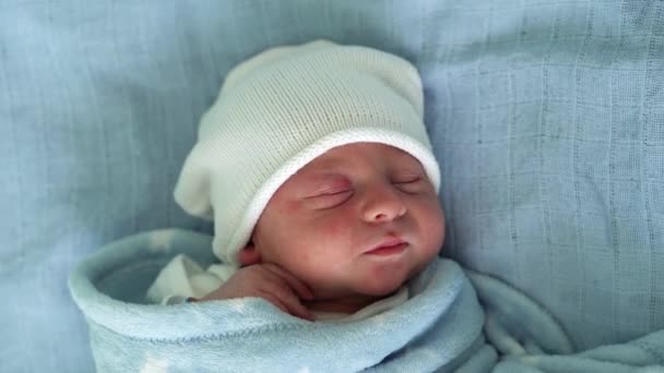 Retrato de rosto de bebê recém-nascido Irritações alérgicas da acne primeiros dias dormindo em fundo azul. Criança no início minutos de vida no chapéu. Bebês, Parto, Primeiros Momentos de Borning, Princípio de Início — Vídeo de Stock