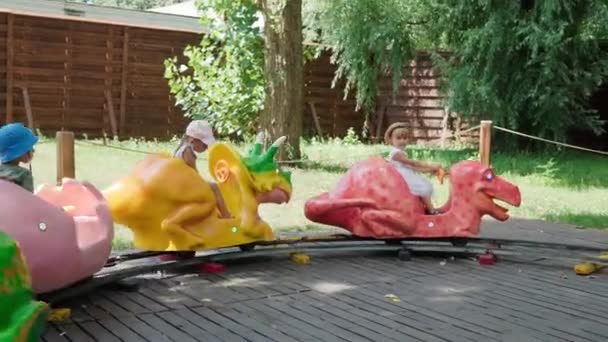 2021.08.12 - Kiev, Ukraine: Little Preschool Children Ride in Circle on Kids Train with Carriages in Shape of Dinosaurs or Animals Have Fun Spend Time. Motorized Dinosaur Predator Mockup in Dinopark — Stock Video