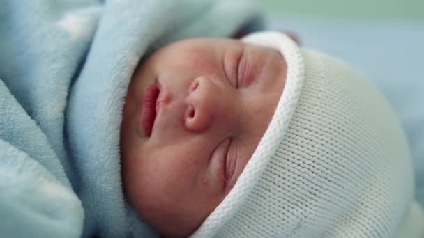 Retrato de la cara del bebé recién nacido Irritaciones alérgicas al acné Primeros días durmiendo sobre fondo azul. Niño al principio Minutos de la vida en sombrero. Bebés, Parto, Primeros Momentos Del Nacimiento, Principio Concepto — Vídeos de Stock