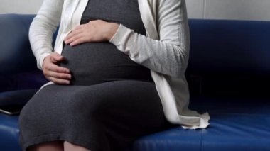 Genç Hamile Koruyucu Maskeli Kadın, hastane için randevu bekleyen koltukta kitap okuyor. Klinikteki jinekoloğu ziyaret et. Muayene Edilmeyi Bekleyen Göbek Sağlığı Kontrolü