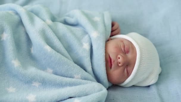 Retrato de la cara del bebé recién nacido Irritaciones alérgicas al acné Primeros días durmiendo sobre fondo azul. Niño al principio Minutos de la vida en sombrero. Bebés, Parto, Primeros Momentos Del Nacimiento, Principio Concepto — Vídeos de Stock