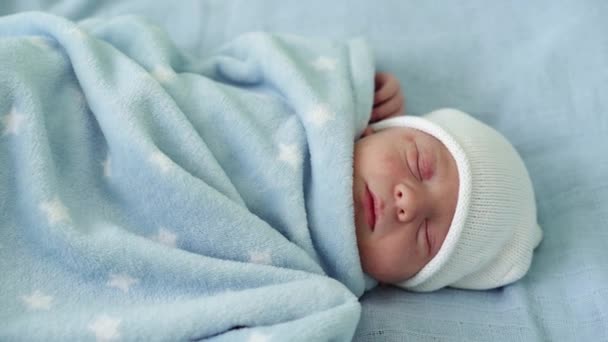 Retrato de rosto de bebê recém-nascido Irritações alérgicas da acne primeiros dias dormindo em fundo azul. Criança no início minutos de vida no chapéu. Bebês, Parto, Primeiros Momentos de Borning, Princípio de Início — Vídeo de Stock