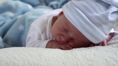 Yakın plan Yeni Doğmuş Bebek Yüzü İlk Günler Mavi Göbek Arkaplanında Tatlı Uyuyan Bebek Portresi. Hayata Başlayan Çocuk Şapka 'da. Bebekler, Doğum, Doğumun İlk Anları, Başlangıç Konsepti