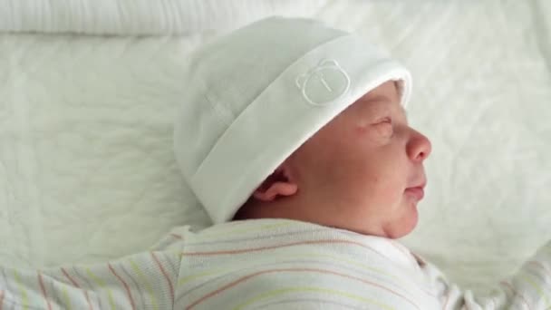 Sveglio neonato Ritratto facciale Acne Irritazioni allergiche Starnuto dei primi giorni su sfondo bianco. Bambino inizio minuti di vita sul cappello. Neonati, Parto, Primi momenti della nascita, Inizio del concetto — Video Stock