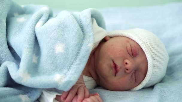 Primo piano del neonato Ritratto del viso Primi giorni Dormire dolcemente su sfondo blu bianco. Bambino all'inizio Minuti di vita sul cappello. Neonati, Parto, Primi momenti della nascita, Inizio del concetto — Video Stock