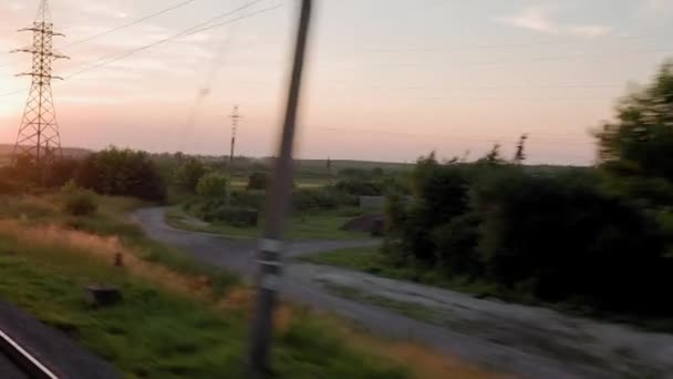 View from window of high-speed train on landscape of beautiful nature wild field and forest on evening cloudy dusk sky sunset in summer background. Transport, travel, railway, communication concept — Stock Video