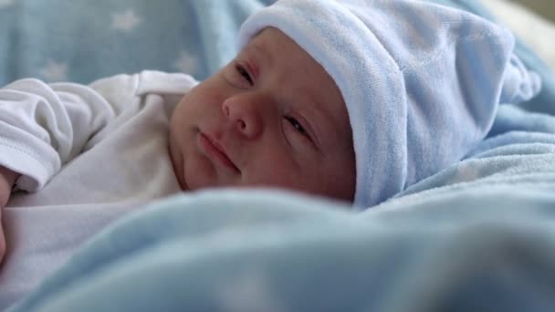 Novorozené dítě tvář Portrét rané dny v makro spánek a otevřené oči na pozadí modré hvězdy. Dítě na začátku minuty života na klobouku. Kojenci, porod, první okamžiky narození, počátky konceptu — Stock video