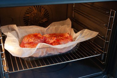 Modern bir mutfakta, parşömen kağıdındaki baharatlı biftek. Evde yemek pişirme, temizlik, sağlıklı beslenme. Yan görünüm, yatay biçim.