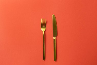 Modaya uygun altın kaplama çatal, çatal, kırmızı kağıt üzerinde bıçak, minimum stil düz döşeme, kopyalama alanı. Restoran, kafe, dağıtım servisi, sosyal medya için. Sevgililer Günü yemeği kavramı. Yatay.
