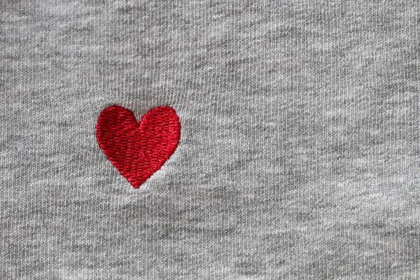 グレーの生地の背景に糸で刺繍された赤いハート クローズアップ マクロ コピースペース フラットレイアウト 3月8日2月14日誕生日バレンタイン母の日のお祝いのコンセプト愛 — ストック写真