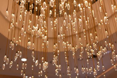 Modern tasarım lamba, sayısız cam saydam şeffaf ampuller şeklinde. Sanat eseri. Moda tasarımı, iç mekanlarda moda. Çerçevesi sıcak renklerle renklendirilmiş. Yumuşak seçici odaklanma. Yatay.