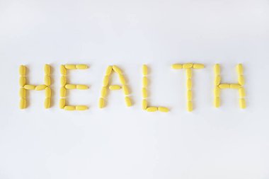 Beyaz arka planda sarı uzun haplar, makro, yakın plan, kopyalama alanı. Besin takviyeleri konsepti, sağlık, vitaminler, 2021 'in moda rengi, aydınlatıcı. Yatay.