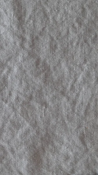 Kırışık keten kumaş arka planının en üst görüntüsü. Çay havlusu, peçete, masa örtüsü ya da giysi yakın plan. Basitlik kavramı, çevre dostluğu, doğal giysiler, ev yapımı tekstil. Dikey.