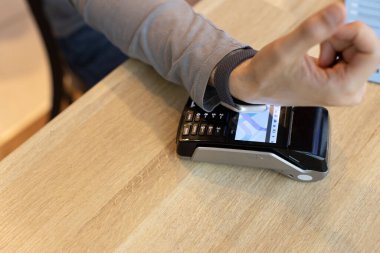 NFC teknolojisi üzerinden akıllı izleme cihazını kullanarak kablosuz ya da temassız ödeme yapan tanınmayan bir adam ödeme terminaline başvurur. E-ticaret kavramı, daha az teknoloji, iş ve nakitsiz iletişim kullanan insanlar..