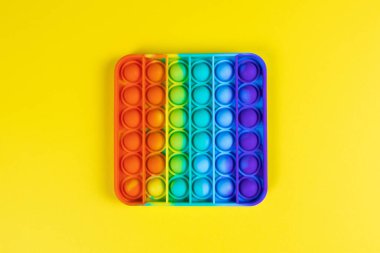 Stres önleyici oyuncak, basit gamzeli, sarı arka planda, kopyalama alanı. Kıpır kıpır çocuklar için konsept eğlence, hassas motor becerilerin gelişimi için duyusal oyuncaklar, stres giderici.