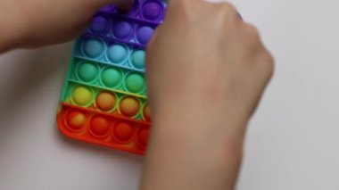 Çocuk stres önleyici oyuncakla oynuyor, beyaz arka planda basit bir gamzesi var. Baloncukları iki parmakla bastırır. Çocuklar için konsept eğlence, hassas motor becerilerin gelişimi için duyusal oyuncaklar.