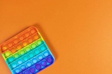 Stres önleyici oyuncak kare, basit gamze, turuncu arka plan, kopyalama alanı. Kıpır kıpır çocuklar için konsept eğlence, hassas motor becerilerin gelişimi için duyusal oyuncaklar, stres giderici.