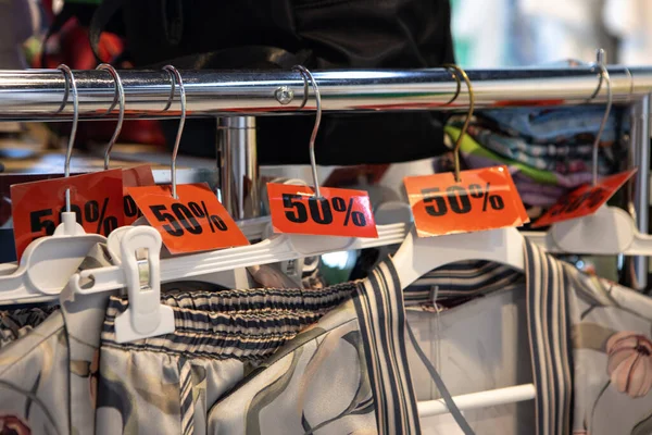 İndirim etiketleri% 50 indirimli. Günlük ya da ev kıyafetleri satan mağazalardaki askılarda. Moda konsepti, indirim sezonu, kara Cuma, çevrimdışı alışveriş, numaralar, tatil satışları, pijamalar. Yan görünüm.