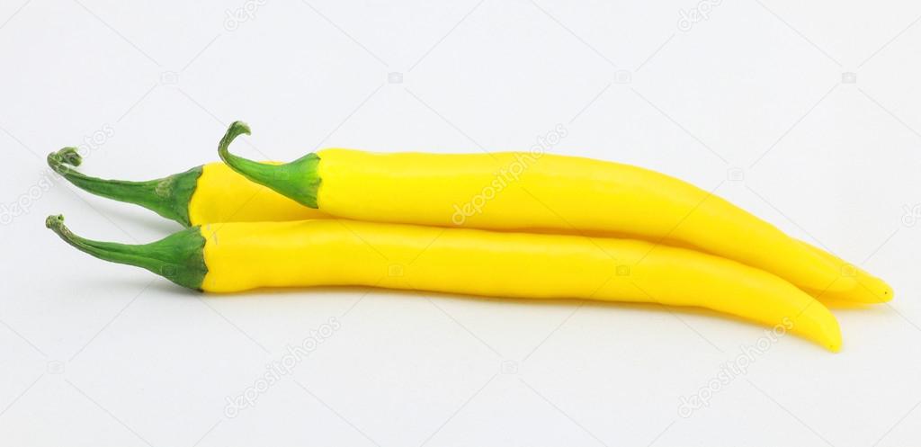 Three chiili peppers in yellow color, isolated on white