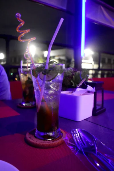 Cocktail, a glass of colorful drink on the table in the night time.