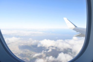 Beyaz bulutların üzerinde uçağın beyaz kanatları uçuşan güzel mavi gökyüzü. Uçak penceresinden görüntüle