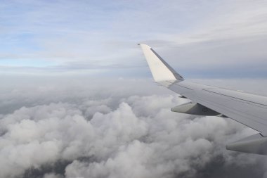 Güzel beyaz bulutlar yüksek açılı havada süzülüyor, uçak penceresinden görülüyor..