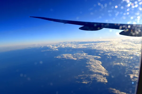 航空機の翼の下に劇的な光と青い空の背景を持つ空の美しい雲 飛行機の窓からの眺め — ストック写真