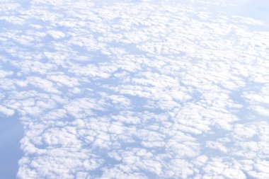 Yüksek irtifadan görünen beyaz bulutlu dramatik gökyüzü. Uçak penceresinden bakıldığında.