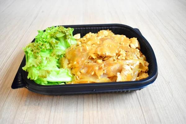 Tayland yemeği, ahşap arka planda plastik tepside siyah soya soslu kızarmış erişte (Pad See Ew). Bangkok, Tayland 'da otel karantinasındaki yolculara hazır yemek.