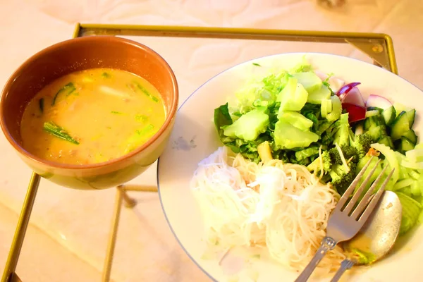 Kanum Jeen Nam Ya or vermicelli rice noodles with chicken coconut milk curry, side dish with a lot of fresh vegetables. Healthy and spicy thai food.