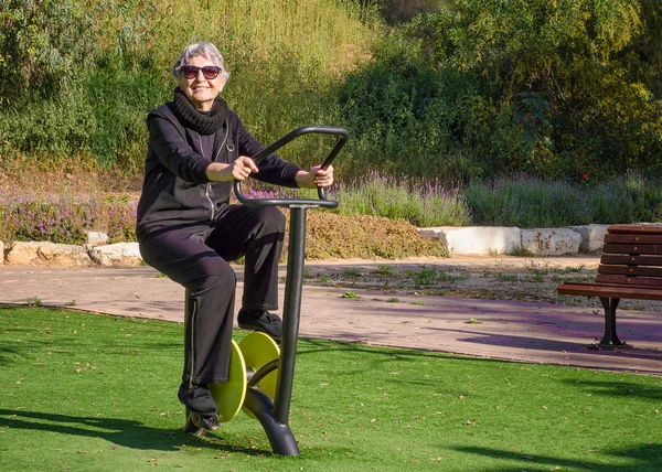 Donna anziana prova la filatura ciclo trainer all'aperto — Foto Stock