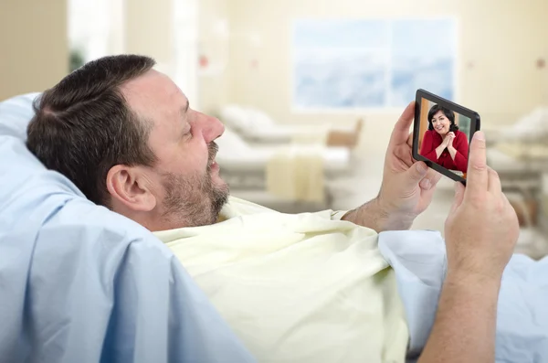 Brodaty mężczyzna na łóżku szpitalnym za pomocą telefonu komórkowego — Zdjęcie stockowe