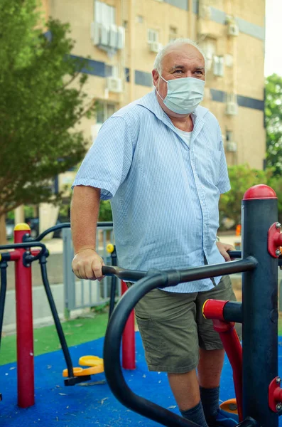 Old Man Face Mask Stands Air Swinger Outdoor Machine His — Stock Photo, Image