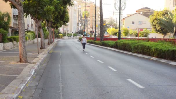 Kvinnan går ensam genom en öde stad gata — Stockvideo