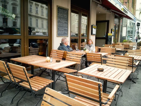Mature couple sitting in an empty street cafe — Stock Photo, Image