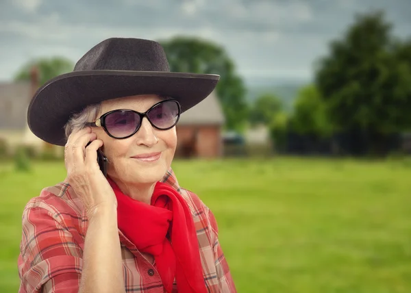 Altes Cowgirl telefoniert mit dem Handy und geht auf Ranch — Stockfoto