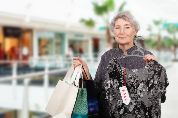 Grå haired kvinna shopping i köpcentrum Stockfoto