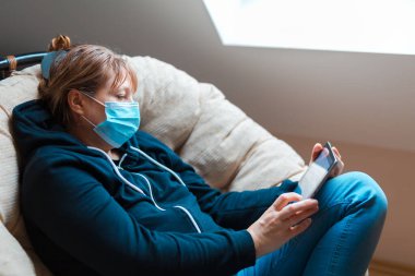 Kadın, evde kendini tecrit altında tutuyor. Sandalyede oturan bir dizüstü bilgisayarda uzaktan çalışma.