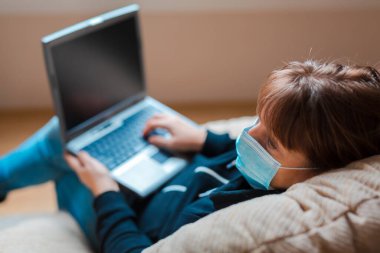 Kadın, evde kendini tecrit altında tutuyor. Sandalyede oturan bir dizüstü bilgisayarda uzaktan çalışma.