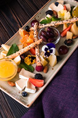 Üzüm ve fındıkla servis edilen peynir tabağı. Çeşit çeşit peynir, peynir, peynir, parmesan peyniri, üzümlü keçi, konfeti çubuğu, kaju, bal ve reçel..