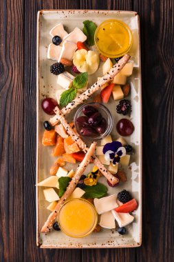 Üzüm ve fındıkla servis edilen peynir tabağı. Çeşit çeşit peynir, peynir, peynir, parmesan peyniri, üzümlü keçi, konfeti çubuğu, kaju, bal ve reçel..