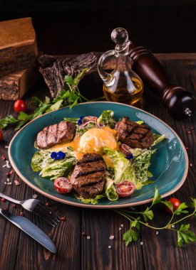 Büyük beyaz bir tabakta sığır etli omlet. Geleneksel İngiliz kahvaltısı Benedict yumurtalı, domatesli, marullu. Benedict yumurtası restoranın arka planında servis ediliyor..