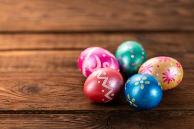 Beş paskalya yumurtası modaya uygun mavi, yeşil, turuncu, mor ve altın renkli eski ahşap masa süslemeleri. Boşluğu Kopyala.
