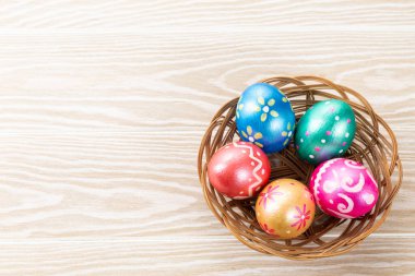 Beş paskalya yumurtası koyu mavi, yeşil, turuncu, morumsu ve mavi arka planda sepetle süslenmiş. Metin için alanı kopyala.